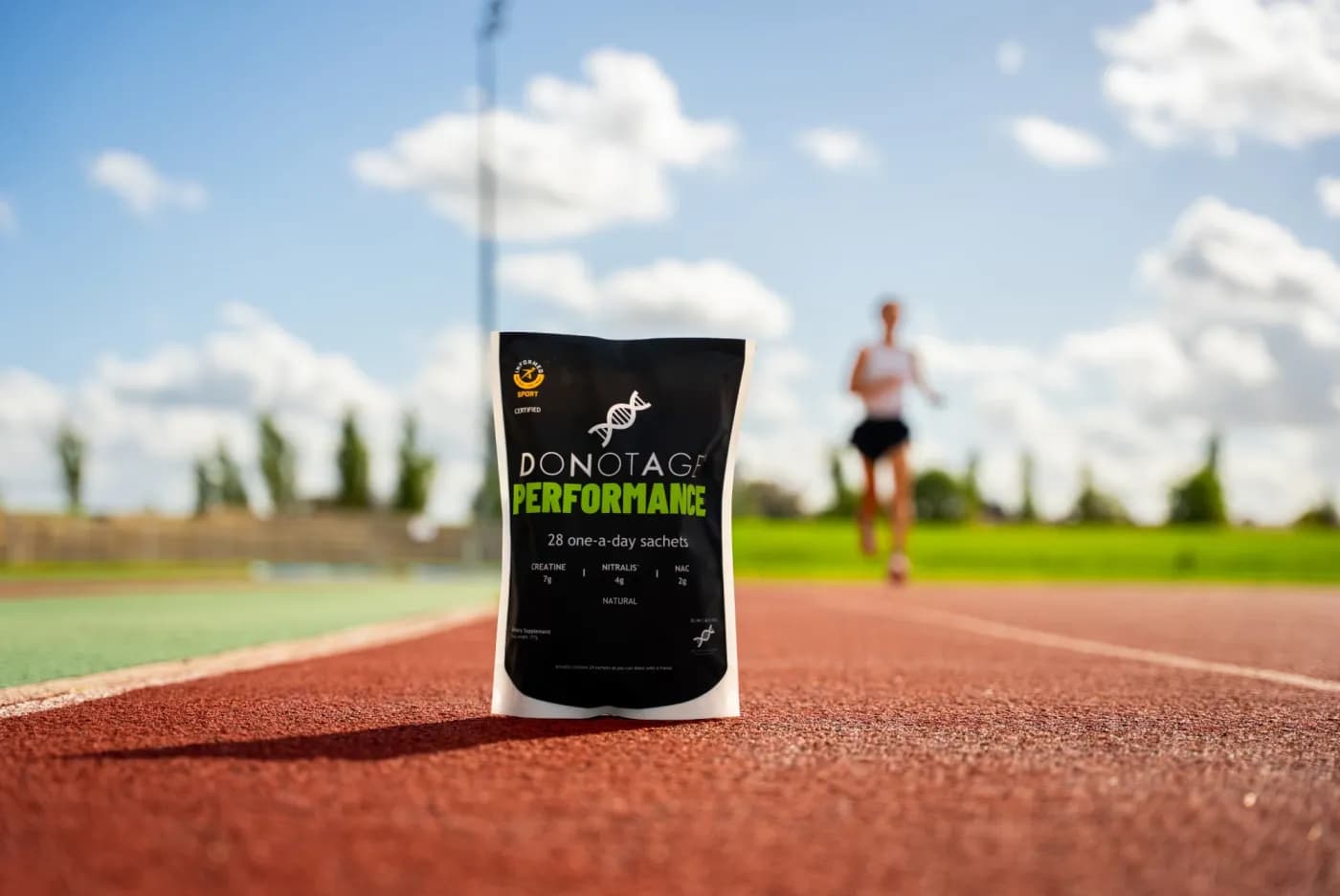 The DoNotAge® Performance pouch on a running track, with a runner behind it