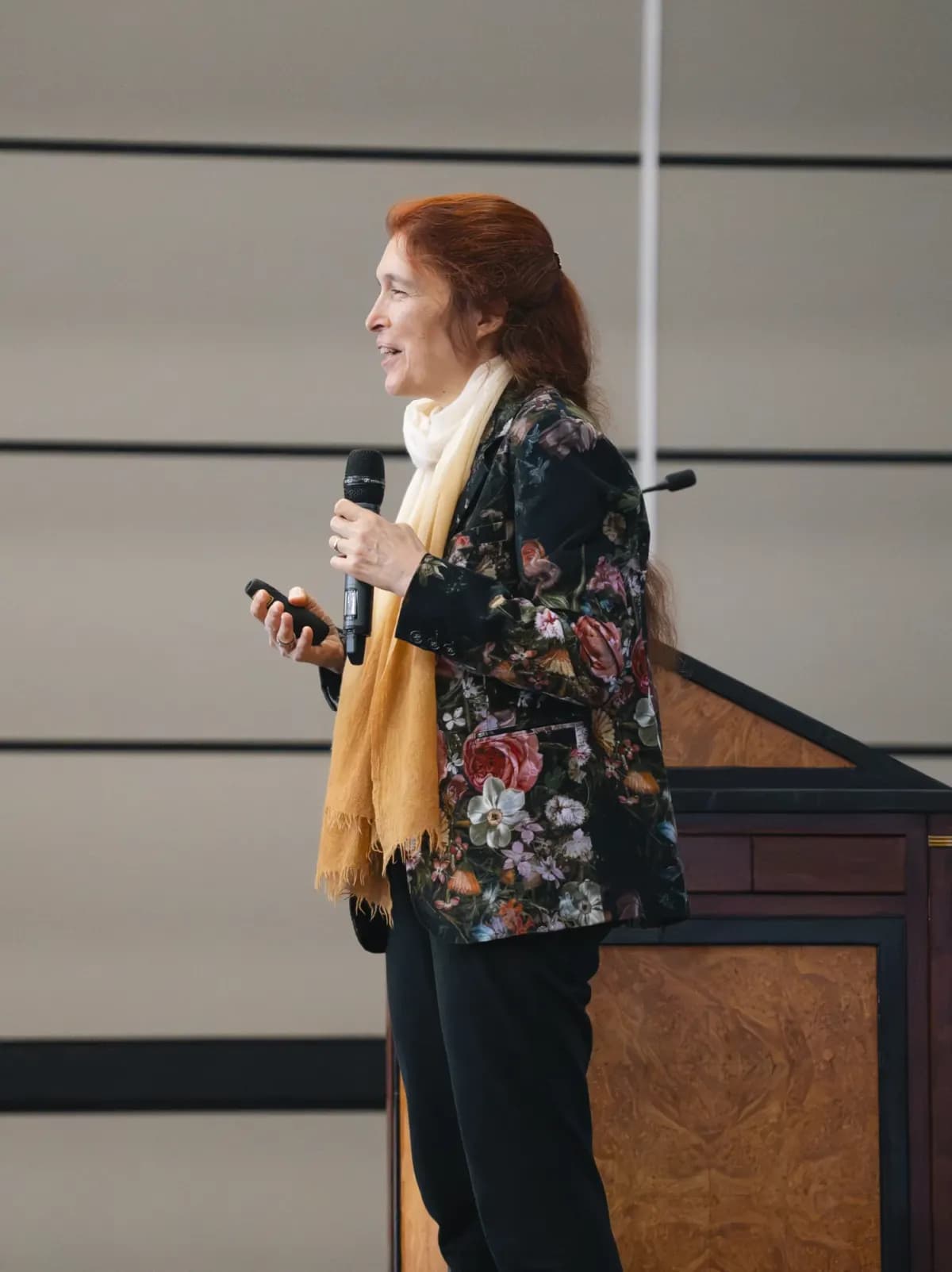 A conference presenter holding a microphone beside the lectern