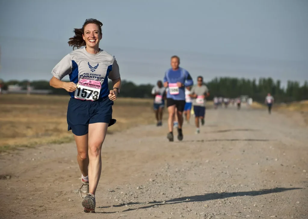 A group of people running a marathon on a dirt road.