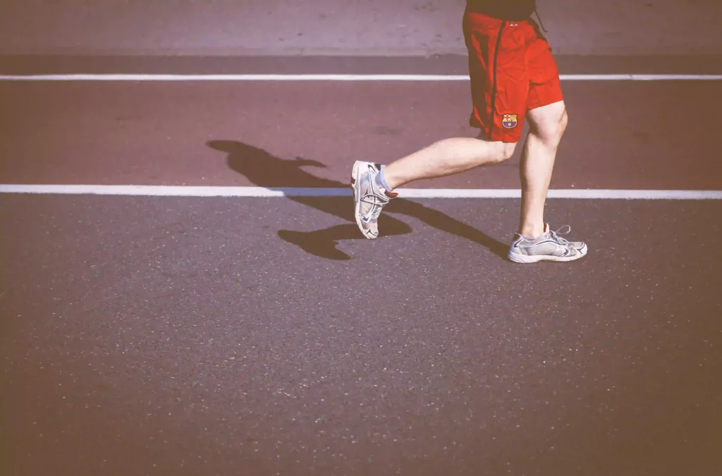 A person running on a track in shorts and trainers.