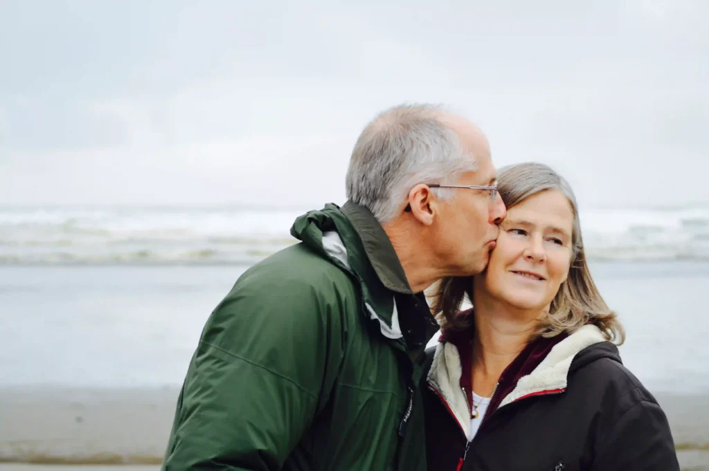 Elderly couple kissing on a beach.